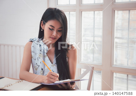 Asian woman holding pencil analysis the graph at the home office for setting challenging business goals And planning to achieve the new target. Asian woman holding pencil analysis the graph at the home office for setting challenging business goals And planning to achieve the new target. 140147588