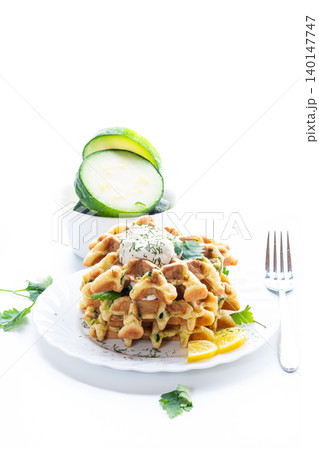 savory zucchini waffles with sour cream on white background savory zucchini waffles with sour cream on white background 140147747