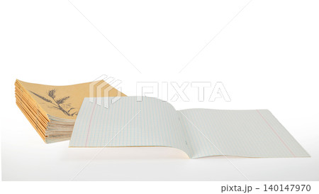 opened school notebook in a cage in front of a stack of craft notepads on a white background opened school notebook in a cage in front of a stack of craft notepads on a white background 140147970
