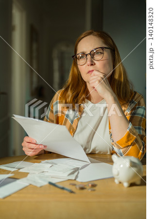 Cost of living crisis concept with worried woman counting coins at home 140148320