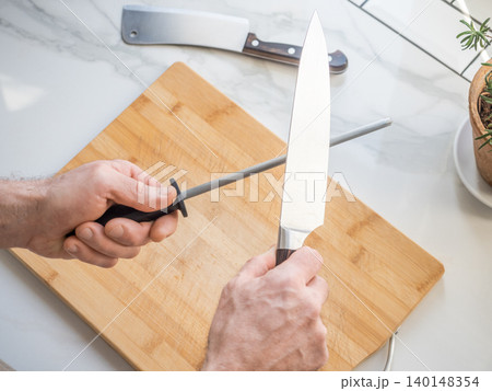 Sharpening a kitchen knife with a honing rod Sharpening a kitchen knife with a honing rod 140148354