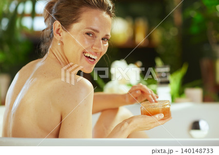Mid-Adult Woman Smiling in Bathtub with Scrub 140148733