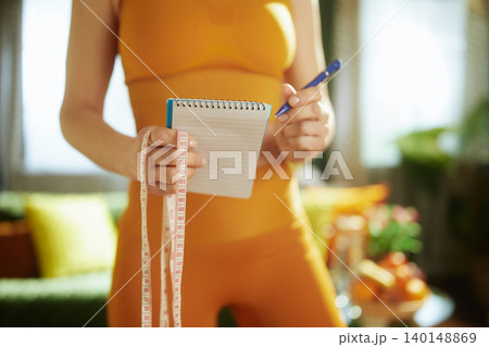 Woman Planning Health Goals with Notebook and Tape Measure 140148869