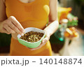 Woman Enjoying Healthy Pumpkin Seeds from a Green Bowl 140148874