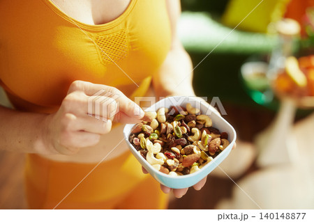 Woman in Orange Activewear with Nut and Fruit Mix Woman in Orange Activewear with Nut and Fruit Mix 140148877