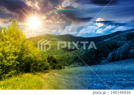 day meet night in beautiful countryside. epic view landscape in mountains on summer solstice. sun and moon in harmony over trail through the grassy field near forested rolling hills. rural scenery day meet night in beautiful countryside. epic view landscape in mountains on summer solstice. sun and moon in harmony over trail through the grassy field near forested rolling hills. rural scenery 140148916