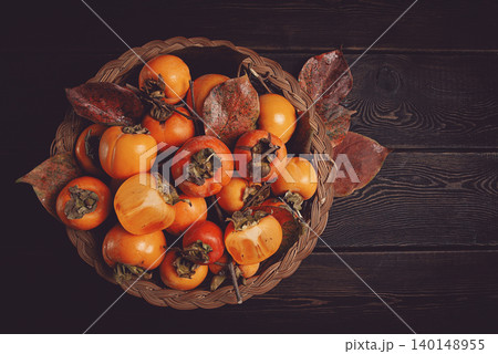 fresh persimmon in a basket, with leaves, top view, no people, fresh persimmon in a basket, with leaves, top view, no people, 140148955