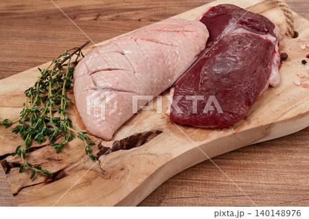 Fresh raw duck breasts, on a wooden chopping board, with herbs and spices, no people Fresh raw duck breasts, on a wooden chopping board, with herbs and spices, no people 140148976