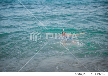 Caucasian man wearing a full face snorkeling mask swims in the Red Sea near Sharm El Sheikh Egypt with turquoise water around him. Beach sea vacation travel resort lifestyle 140149287