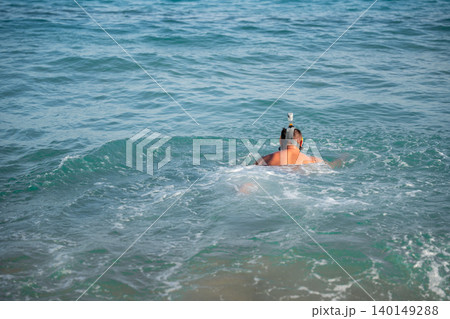 Caucasian man wearing a full face snorkeling mask swims in the Red Sea near Sharm El Sheikh Egypt with turquoise water and small waves. Beach sea vacation recreation resort lifestyle Caucasian man wearing a full face snorkeling mask swims in the Red Sea near Sharm El Sheikh Egypt with turquoise water and small waves. Beach sea vacation recreation resort lifestyle 140149288