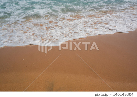 White sea foam washes onto a sandy beach in Sharm El Sheikh Egypt with clear water along the Red Sea shoreline in daylight. Beach resort lifestyle 140149304