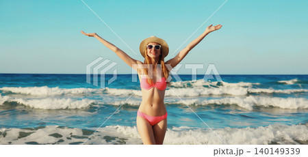 Summer vacation, beautiful happy woman in bikini swimsuit raising her hands up on the beach at sea Summer vacation, beautiful happy woman in bikini swimsuit raising her hands up on the beach at sea 140149339