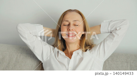 Happy relaxed young woman enjoying at home, satisfied girl sitting on the couch in living room 140149433