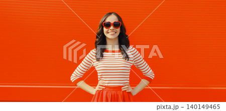 Beautiful happy smiling young brunette woman posing in red heart shaped sunglasses, skirt in city 140149465