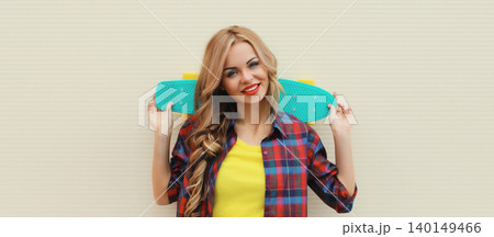 Stylish young blonde woman posing with skateboard on city street Stylish young blonde woman posing with skateboard on city street 140149466