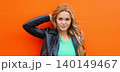 Portrait beautiful young blonde woman posing in black leather jacket on colorful orange background 140149467