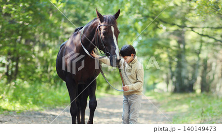 Teenager boy kid with horse walking in summer forest, horseback riding 140149473