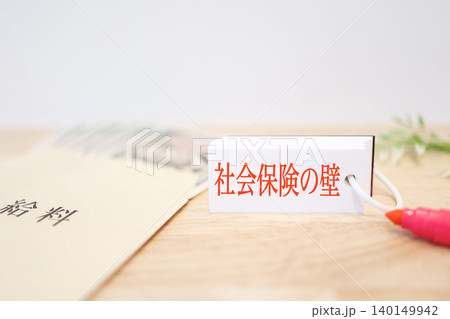 社会保険の壁。給料の封筒。赤文字で記載されたカード。コピースペースあり 社会保険の壁。給料の封筒。赤文字で記載されたカード。コピースペースあり 140149942