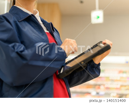 タブレット操作中の女性店員 タブレット操作中の女性店員 140151400