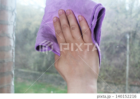 The girl wipes the window with a napkin. Close-up 140152216