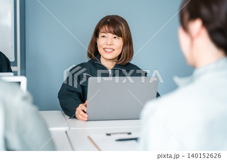 オフィス,事務所でミーティング,打ち合わせする作業着姿の女性従業員 オフィス,事務所でミーティング,打ち合わせする作業着姿の女性従業員 140152626