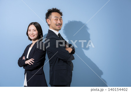 腕組みをして背中合わせのカメラ目線のスーツのビジネスマン男女 笑顔のリーダーシップやbtobイメージ 腕組みをして背中合わせのカメラ目線のスーツのビジネスマン男女 笑顔のリーダーシップやbtobイメージ 140154402