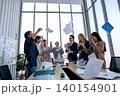 Happy business team celebrating success in office by throwing documents in the air. Corporate achievement, teamwork, motivation, workplace happiness, and startup success concept. 140154901