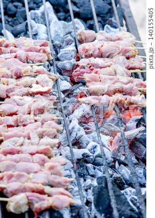 Raw meat skewers grilling on charcoal grill	 140155405