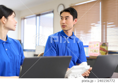 介護施設で事務で話をするアジア人介護士 介護施設で事務で話をするアジア人介護士 140156772