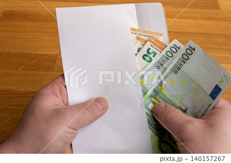 Hands holding envelope with Euro cash, salary in envelope or bribery concept Hands holding envelope with Euro cash, salary in envelope or bribery concept 140157267