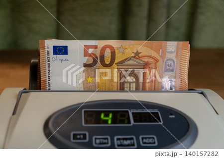 Cash counting machine with 50 Euro banknotes stack close up Cash counting machine with 50 Euro banknotes stack close up 140157282