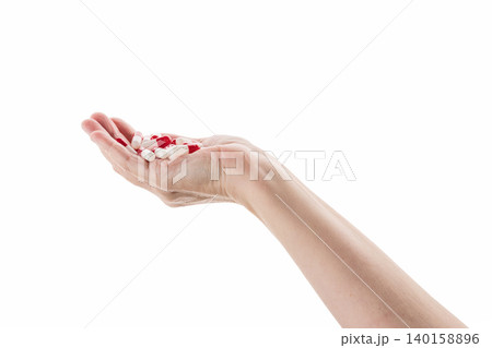 Mid aged female hand full of red and white pills isolated on white Mid aged female hand full of red and white pills isolated on white 140158896