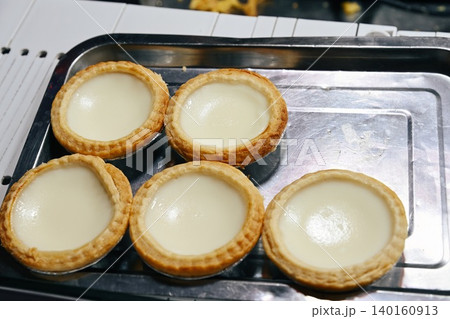 Traditional fresh milk tarts on metal tray for sale at Temple Street Night Market street food stall under evening lights in Hong Kong Traditional fresh milk tarts on metal tray for sale at Temple Street Night Market street food stall under evening lights in Hong Kong 140160913