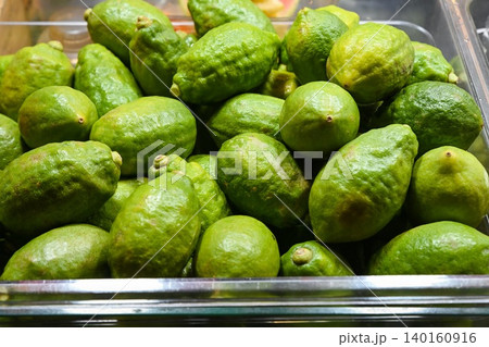 Fresh green citrons or perfume lemons in plastic box container for sale at Temple Street Night Market street food market stall in Hong Kong Fresh green citrons or perfume lemons in plastic box container for sale at Temple Street Night Market street food market stall in Hong Kong 140160916