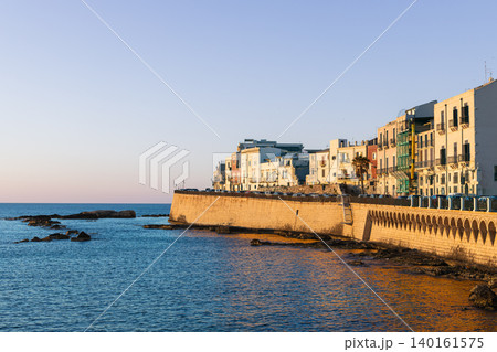 Golden sunrise light waterfront coastal Italian town living district picturesque settlement with ancient stone walls and colorful building tranquil Mediterranean sea 140161575