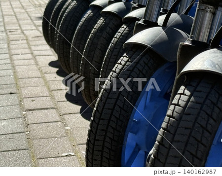 Bicycle rental station in urban area with focus on tires and blue wheel rim 140162987