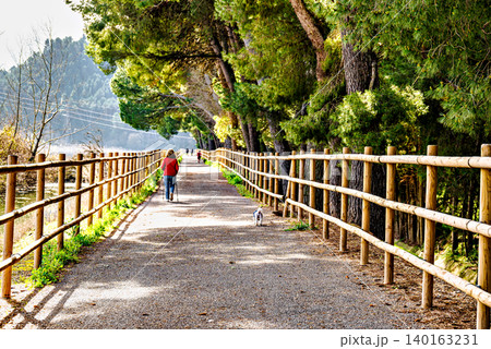 Woman walking her dog along the path by the reservoir in the Sant Llorenc de Montgai Nature Reserve, Noguera region, Lleida, Catalonia 140163231