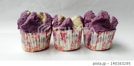 Close-up photo of three purple and white steamed cakes served in floral paper cups. Close-up photo of three purple and white steamed cakes served in floral paper cups. 140163295