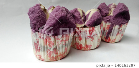 Close-up photo of three purple and white steamed cakes served in floral paper cups. Close-up photo of three purple and white steamed cakes served in floral paper cups. 140163297