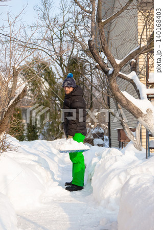 Man in winter jacket shoveling snow with shovel in front of brick house after heavy snowfall Man in winter jacket shoveling snow with shovel in front of brick house after heavy snowfall 140168403