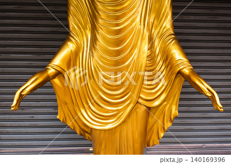 Close-up of Golden Buddha Statue Hands and Robe against Metal Shutter Background Close-up of Golden Buddha Statue Hands and Robe against Metal Shutter Background 140169396