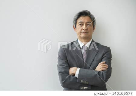 カメラ目線で腕組みをしたスーツ姿の60代の男性 カメラ目線で腕組みをしたスーツ姿の60代の男性 140169577
