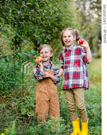 Two happy children holding red apples orchard during autumn harvest enjoying fresh organic fruit Two happy children holding red apples orchard during autumn harvest enjoying fresh organic fruit 140169598