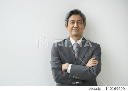カメラ目線で微笑む腕組みをしたスーツ姿の60代の男性 140169600