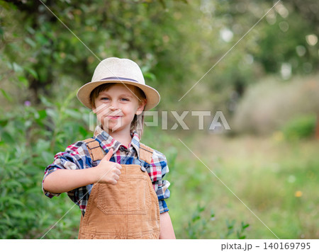 Boy in hat holding bitten red apple and showing thumbs up Boy in hat holding bitten red apple and showing thumbs up 140169795