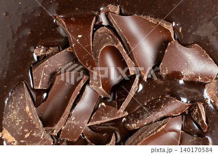 Dark chocolate chunks into liquid melted chocolate sauce background Dark chocolate chunks into liquid melted chocolate sauce background 140170584