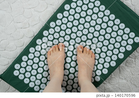 Female feet standing on acupuncture massage mat top view Female feet standing on acupuncture massage mat top view 140170596