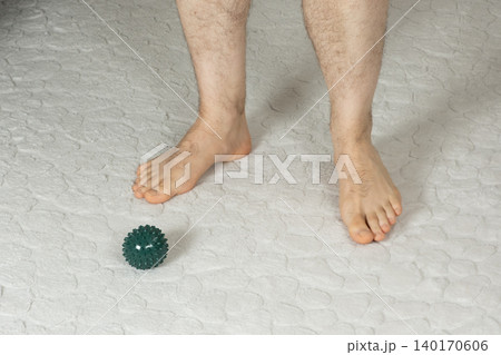 Barefoot Man Standing Near Massage Ball on a Carpet 140170606