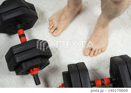 Man preparing for home gym workout with adjustable weights top view Man preparing for home gym workout with adjustable weights top view 140170609