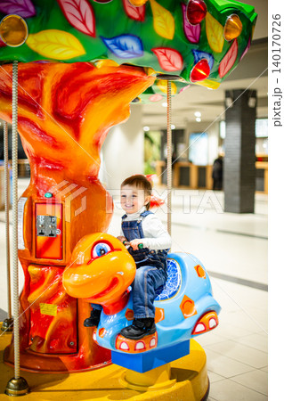 Little boy riding colorful carousel turtle shopping mall amusement area bright decorations Little boy riding colorful carousel turtle shopping mall amusement area bright decorations 140170726